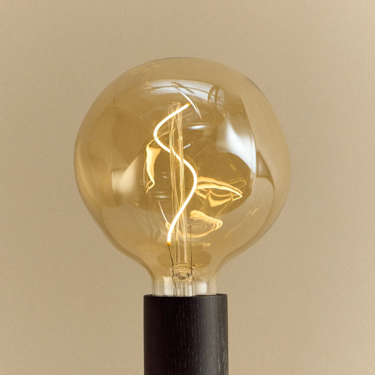 Blackened oak table lamp, tinted globe bulb, close-up of the spiral filament