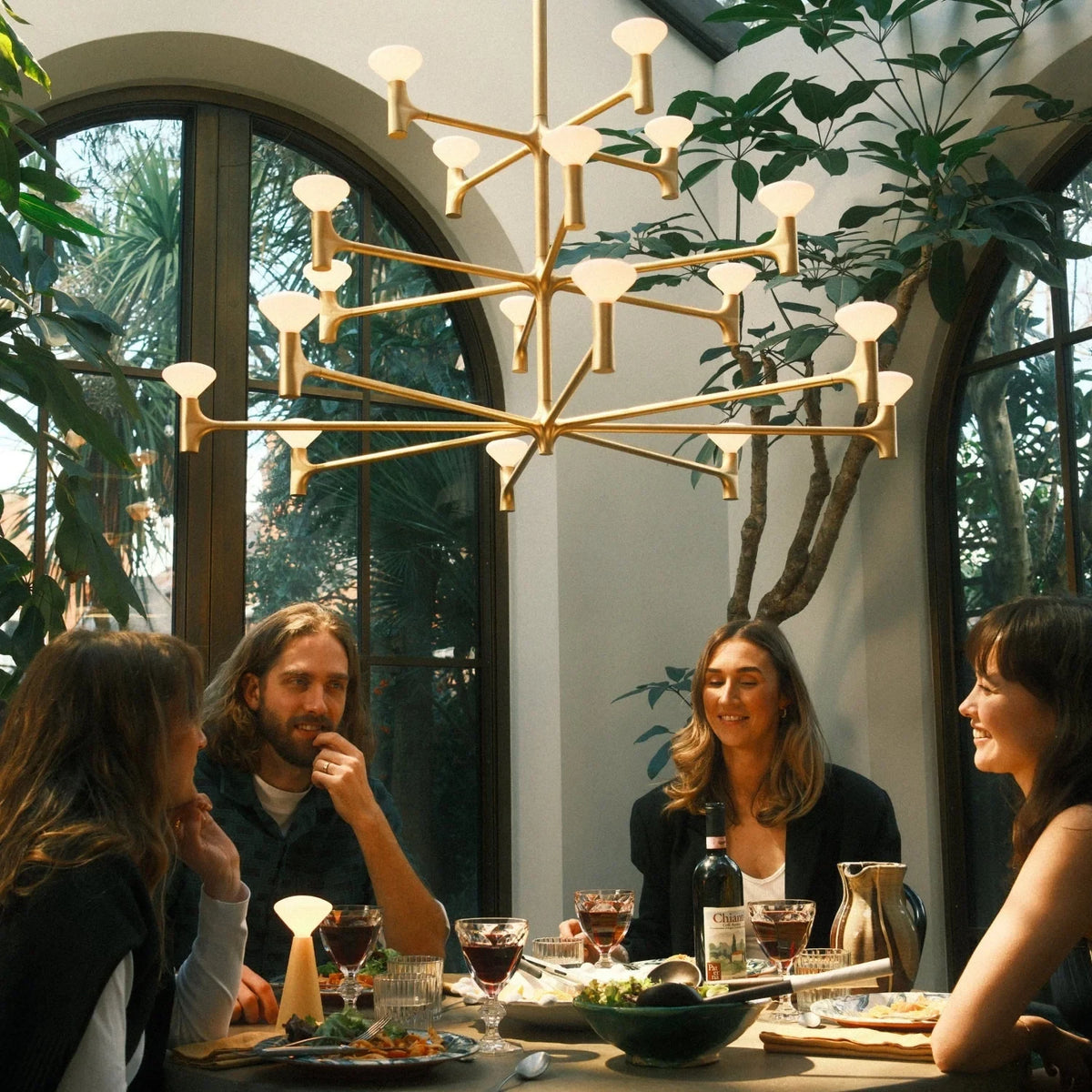 Branching brass chandelier, above a dining table with guests