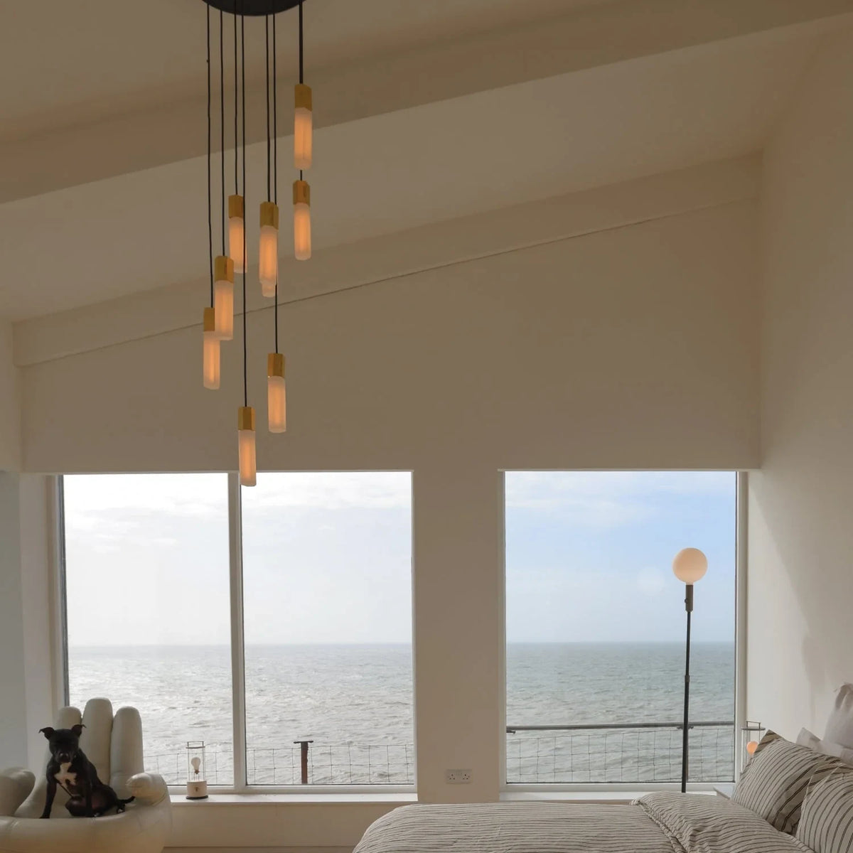 Nine-drop cluster pendant in cast brass with glass bulbs, in a tall living room