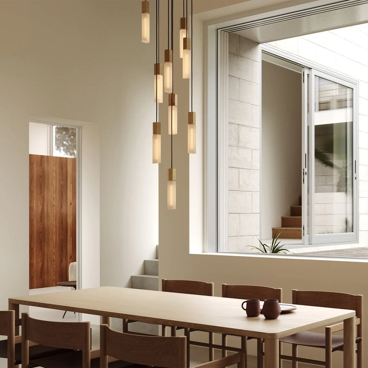Nine-drop cluster pendant in cast brass with glass bulbs, over a dining table