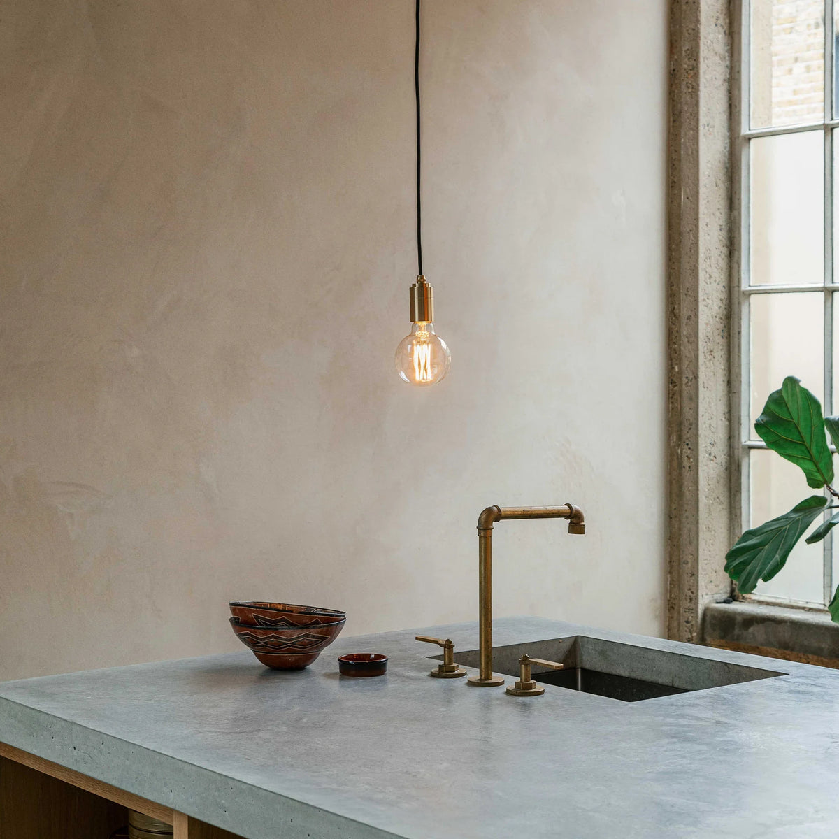 Brass pendant with non-tinted glass filament bulb, over a kitchen counter