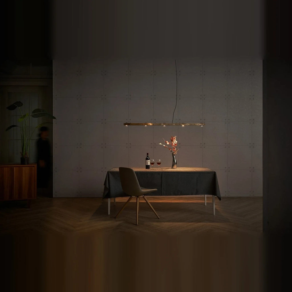 Brass track LED pendant, above a dining table at night