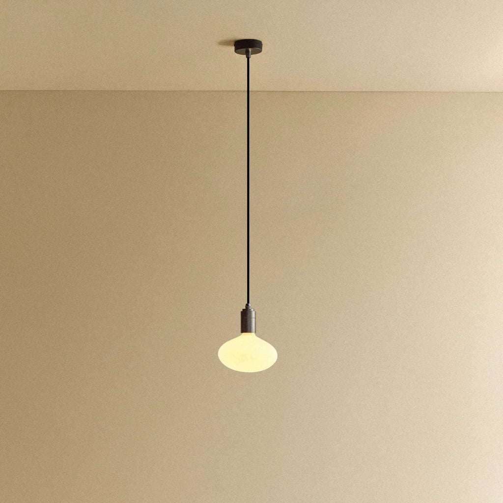 Broad dome matte white glass pendant, graphite, lit, against a plain wall