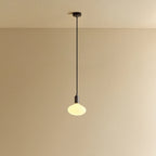 Broad dome matte white glass pendant, graphite, lit, against a plain wall