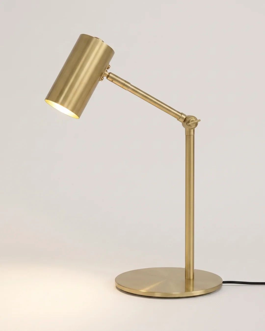 Brushed gold desk lamp with an adjustable arm, on a white background