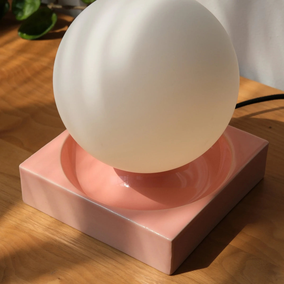 Ceramic cube table lamp with a blown glass globe, in pink, close-up