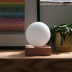 Ceramic cube table lamp with a blown glass globe, in pink with a picture behind