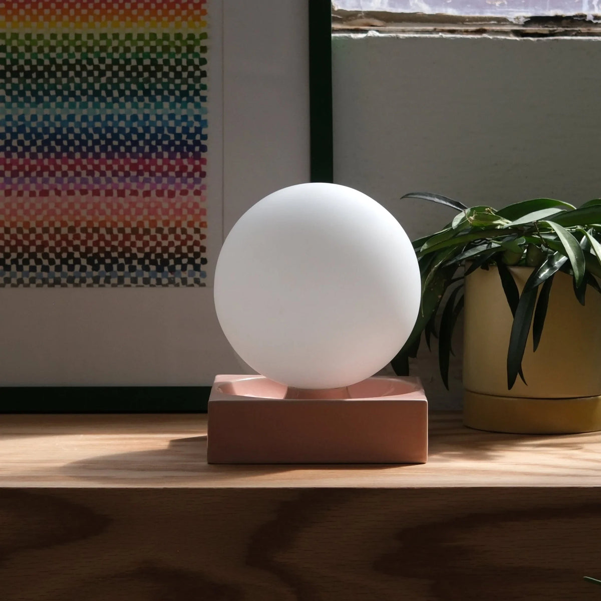 Ceramic cube table lamp with a blown glass globe, in pink with a picture behind