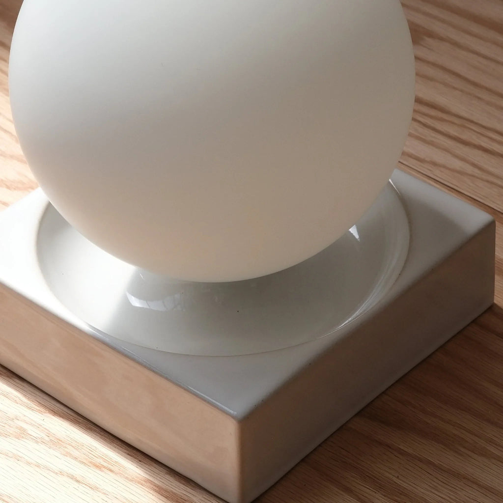 Ceramic cube table lamp with a blown glass globe, in white, close-up