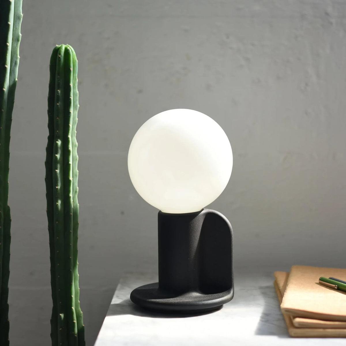 Ceramic table lamp with a paddle handle, in black, lit