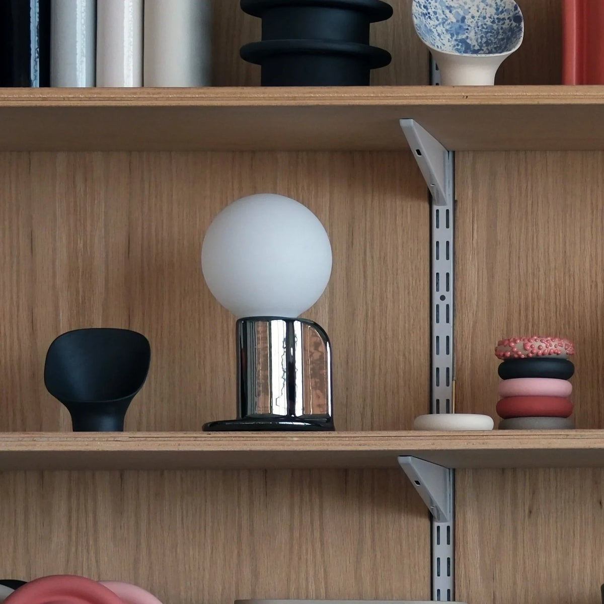 Ceramic table lamp with a paddle handle, in white on a shelf