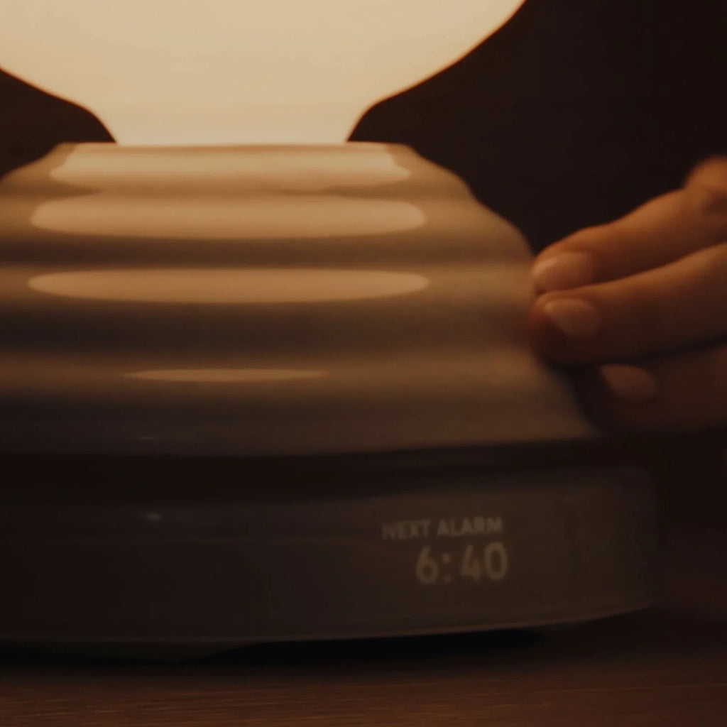 Ceramic wake light lamp pair, hand on the base, showing alarm time