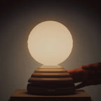 Ceramic wake light lamp pair, lit, hand on the base