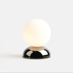 Chrome-glazed rippled table lamp with glass globe, lit, on a plain background