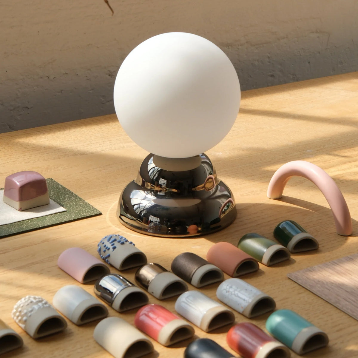 Chrome-glazed rippled table lamp with glass globe, beside glaze samples