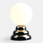 Chrome-glazed rippled table lamp with glass globe, lit, on a plain background