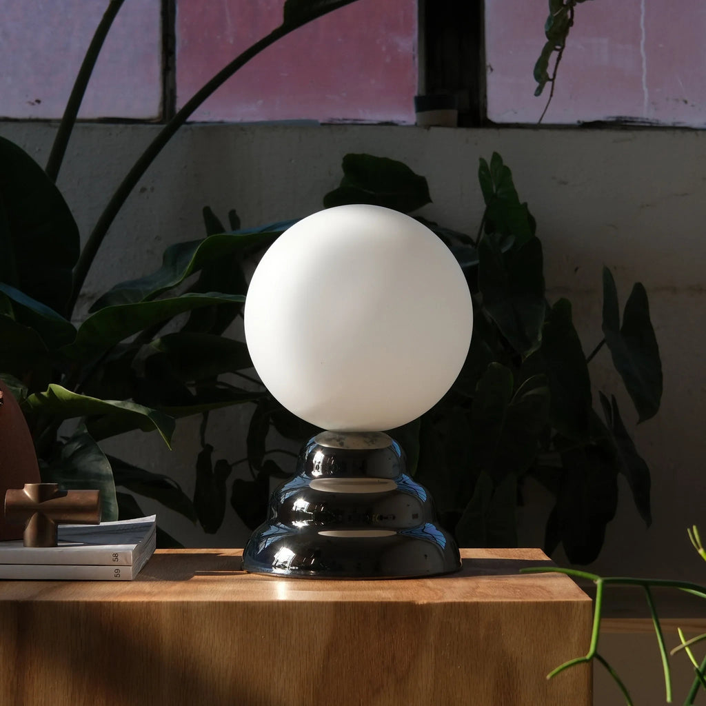 Chrome-glazed rippled table lamp with glass globe, on a wooden block