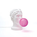 Classical bust table lamp with a pink bubblegum bubble, side view, lit