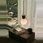 Concrete and glass globe pendant, above a wooden side table