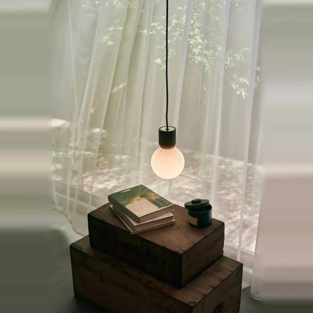 Concrete and glass globe pendant, by a window with curtains