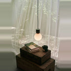 Concrete and glass globe pendant, by a window with curtains