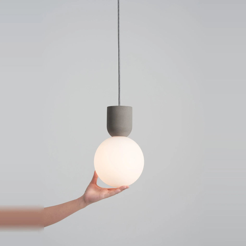 Concrete and glass globe pendant, held by hand