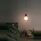 Concrete and glass globe pendant, lit in a bedroom