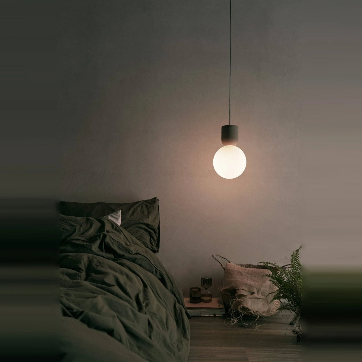 Concrete and glass globe pendant, lit in a bedroom