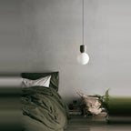 Concrete and glass globe pendant, beside a bed