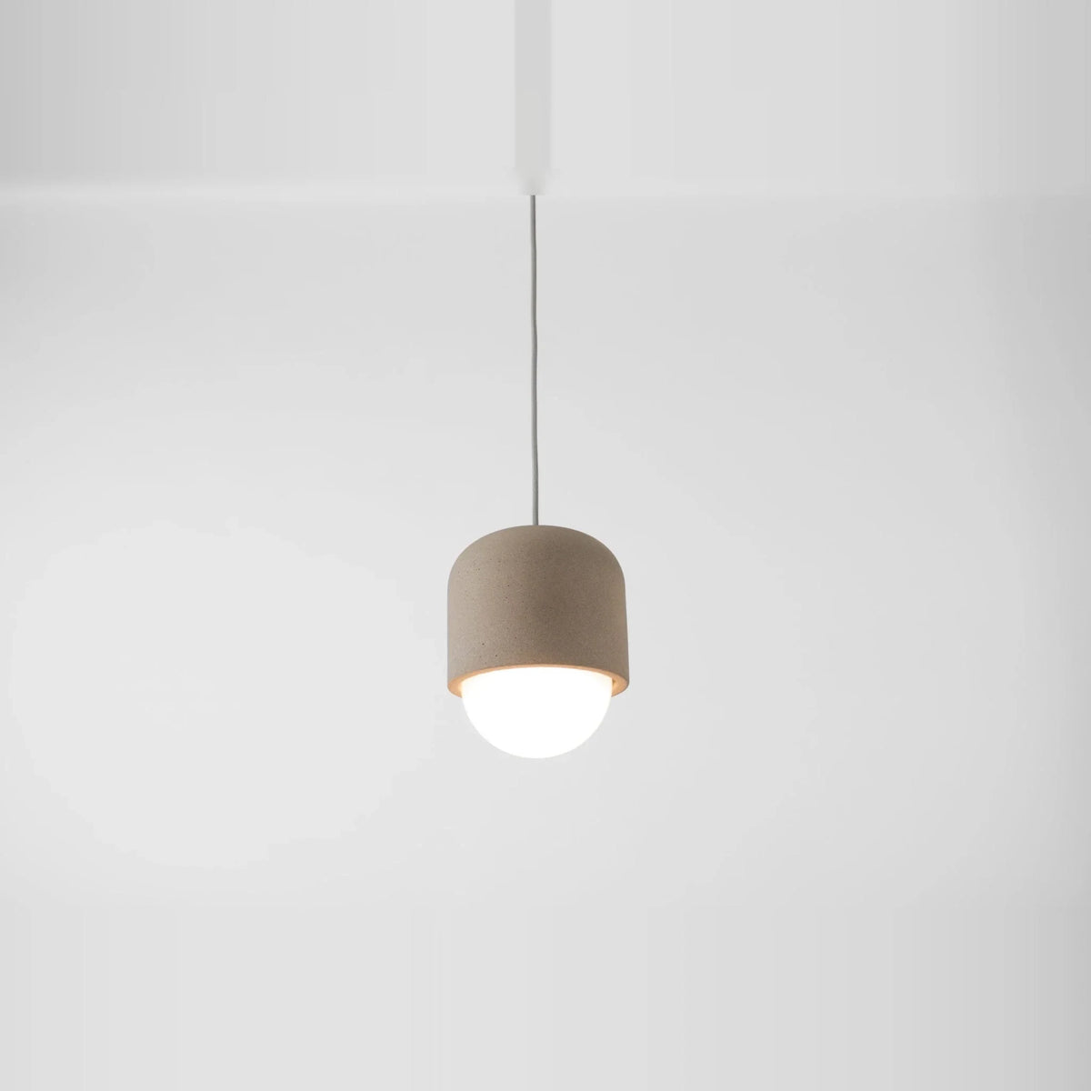 Concrete and opal glass mini pendant, against a white wall