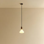 Conical matte white glass pendant, walnut, lit, against a plain wall