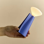 Cordless portable conical table lamp, speckled blue, held in a hand