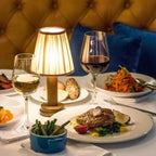 Cordless pleated shade table lamp, lit beside a dinner plate