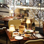 Cordless pleated shade table lamp, lit on a restaurant table
