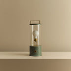 Cordless lantern lamp, green finish, unlit, on a plain ledge