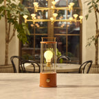 Cordless lantern lamp, orange finish, on a round table by the window