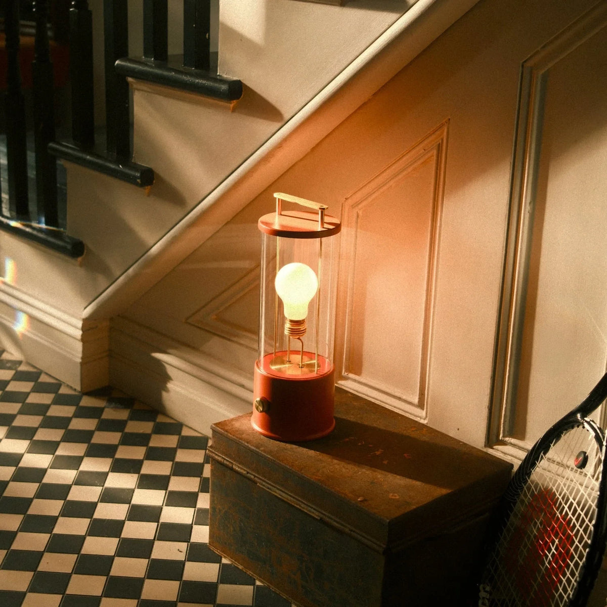 Cordless lantern lamp, orange finish, on a chest by the staircase