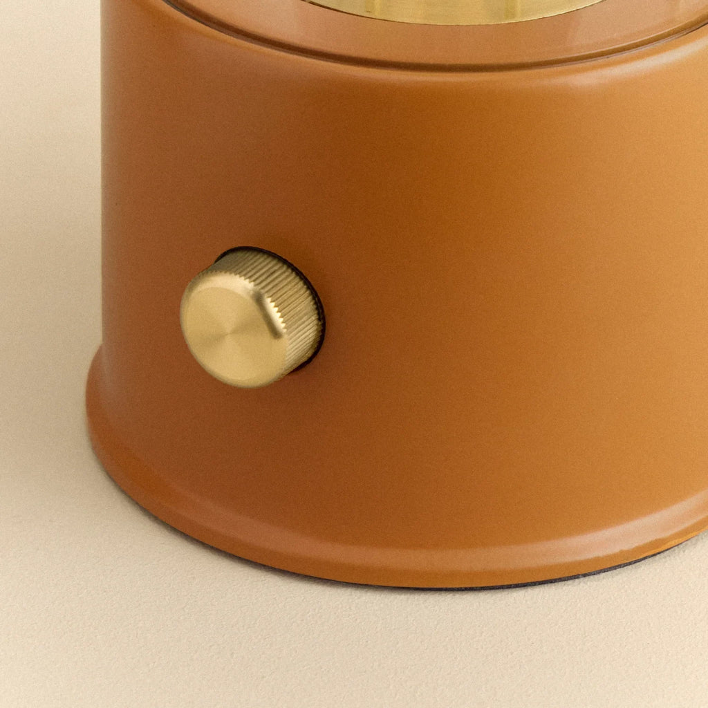 Cordless lantern lamp, orange finish, close-up of the brass control knob