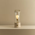 Cordless lantern lamp, plaster pink finish, lit, on a plain ledge