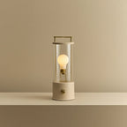 Cordless lantern lamp, plaster pink finish, lit, on a plain ledge