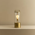 Cordless lantern lamp, solid brass, lit, on a plain ledge