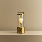 Cordless lantern lamp, solid brass, lit, on a plain ledge