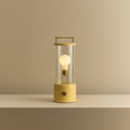 Cordless lantern lamp, yellow finish, lit, on a plain ledge
