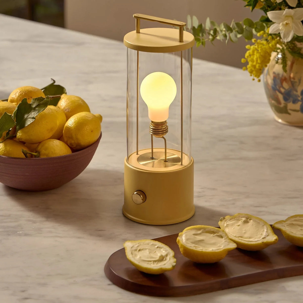 Cordless lantern lamp, yellow finish, on a worktop beside lemons