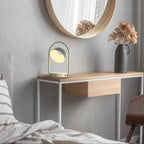 Cordless oval loop table lamp, champagne gold, on a console with a mirror