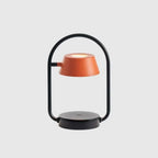 Cordless oval loop table lamp, coral orange, on a plain background