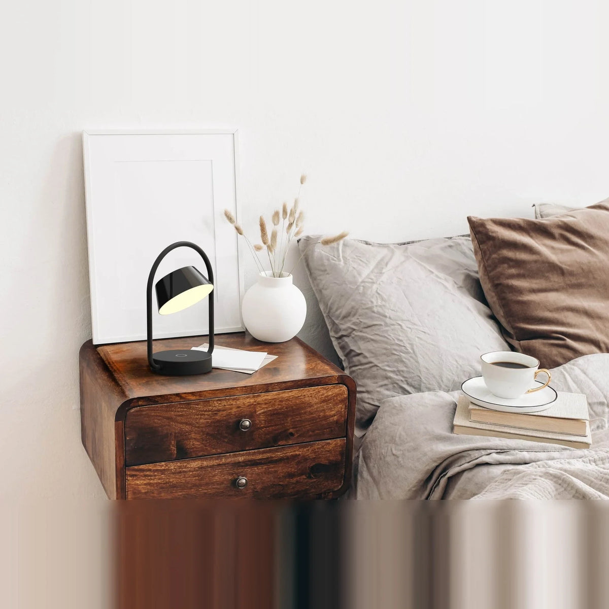 Cordless oval loop table lamp, black, on a bedside table