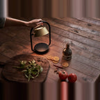 Cordless oval loop table lamp, champagne gold, carried over a table of food