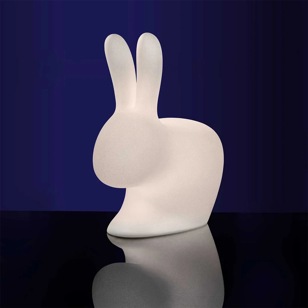 Cordless rabbit-shaped table lamp and seat, translucent, lit against a blue background