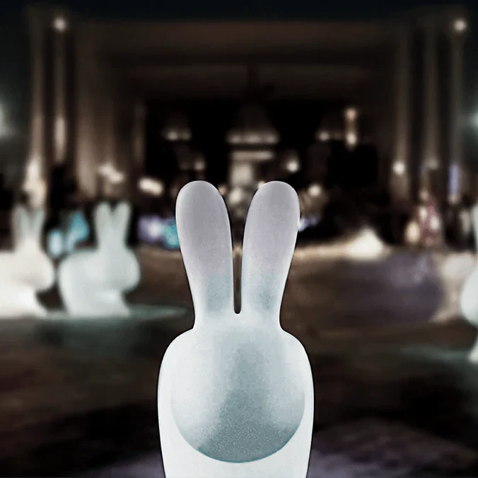 Cordless rabbit-shaped table lamp and seat, translucent, front view, lit, at night